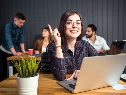 Frau vor Laptop hebt den Finger