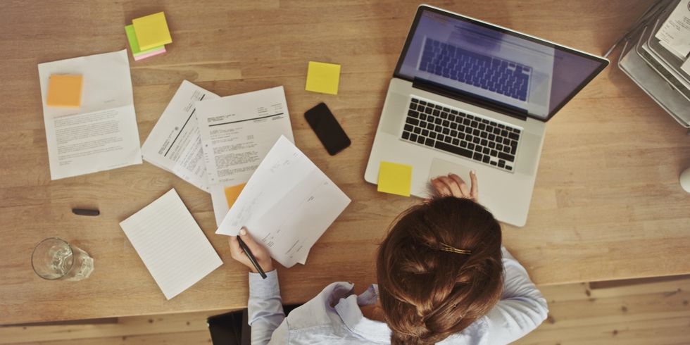 Büroangestellte arbeitet am Laptop und mit Dokumenten