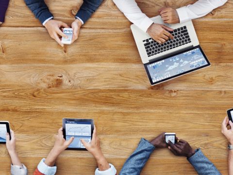 Blick von oben auf eine Gruppe von Menschen mit Tablets, Smartphones und Computern