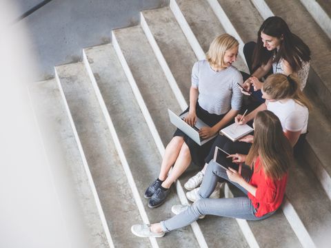 Frauengruppe sitzt auf einer Treppe und arbeitet